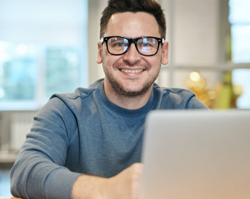 A smiling man working on a laptop